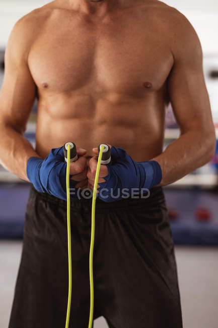 Visão frontal seção média do boxeador masculino segurando uma corda pulando em um ginásio de boxe — Fotografia de Stock