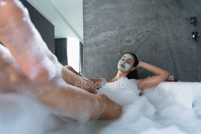Вид на молоду Кавказьку жінку в особі Pack, лежачи в пінній ванні з ногами підняв на краю ванни — стокове фото