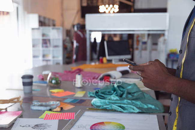 Seitenansicht mittlerer Abschnitt eines männlichen Modestudenten mit einem Smartphone in einem Studio der Modehochschule — Stockfoto