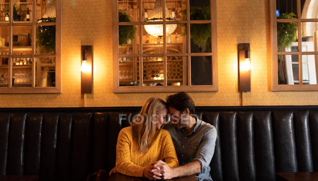 Vista frontal de um jovem casal caucasiano feliz relaxando juntos em férias em um bar, abraçando e de mãos dadas — Fotografia de Stock