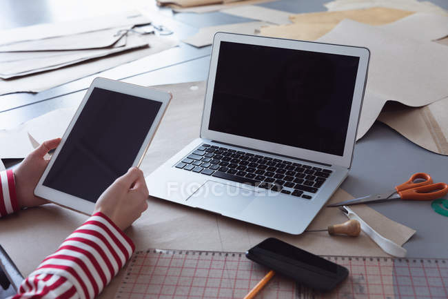Nahaufnahme der Hände einer Modestudentin mit einem Tablet-Computer und einem Laptop während der Arbeit an einem Design in einem Studio der Modehochschule — Stockfoto