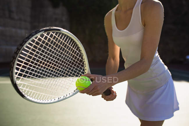 Vue de côté gros plan de la femme jouant au tennis par une journée ensoleillée, se préparant à servir — Photo de stock