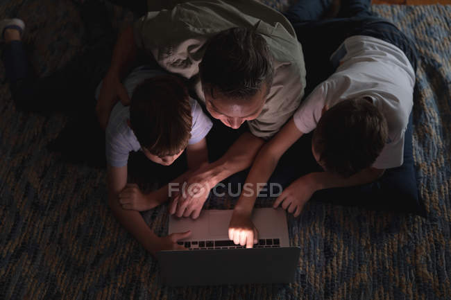 Overhead view of a middle aged Caucasian man and his pre teen sons using a laptop computer in a sitting room — Stock Photo