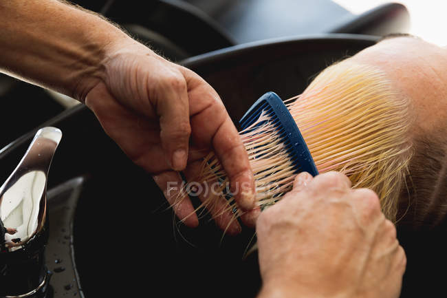 Gros plan d'un coiffeur masculin et d'une jeune femme caucasienne se faisant laver et peigner les cheveux dans un salon de coiffure — Photo de stock