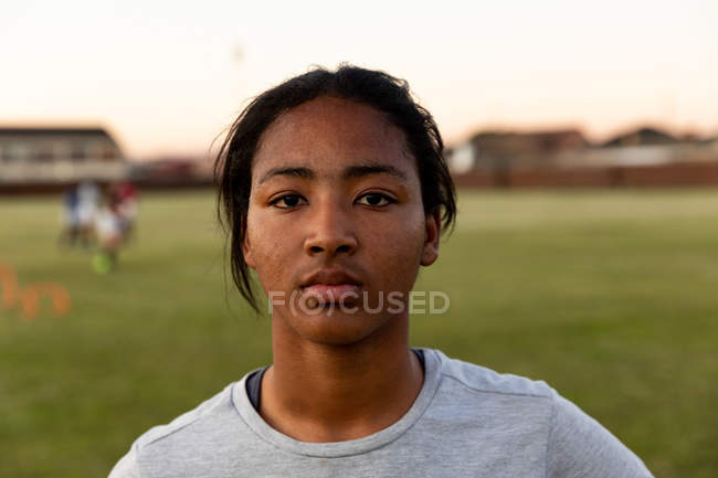 Portrait gros plan d'une jeune joueuse de rugby de race mixte adulte debout sur un terrain de rugby regardant vers la caméra — Photo de stock