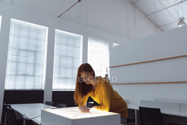 Вид спереди на молодую кавказскую студентку, работающую над дизайнерским рисунком на светофоре в студии колледжа моды — стоковое фото