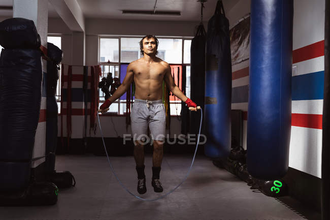 Vista frontal de um jovem boxeador misto pulando em um ginásio de boxe — Fotografia de Stock