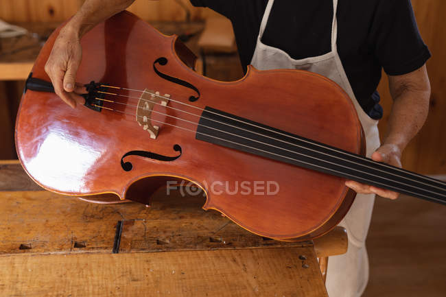 Vista frontal close up de luthier feminino segurando um violoncelo em sua oficina — Fotografia de Stock