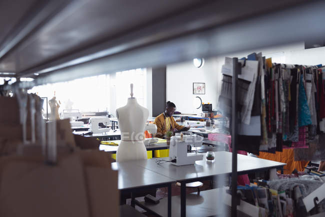 Вид сбоку на молодого афроамериканского студента моды, работающего над дизайном в студии колледжа моды — стоковое фото