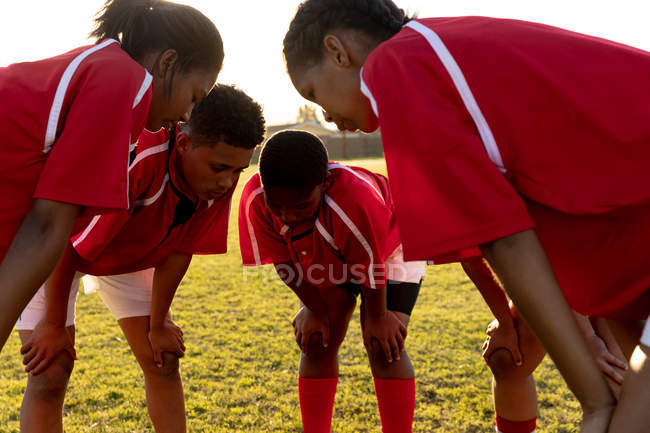 Side view of a team of young adult multi-ethnic female rugby players standing in a huddle on a rugby pitch relaxing after a rugby match — Stock Photo