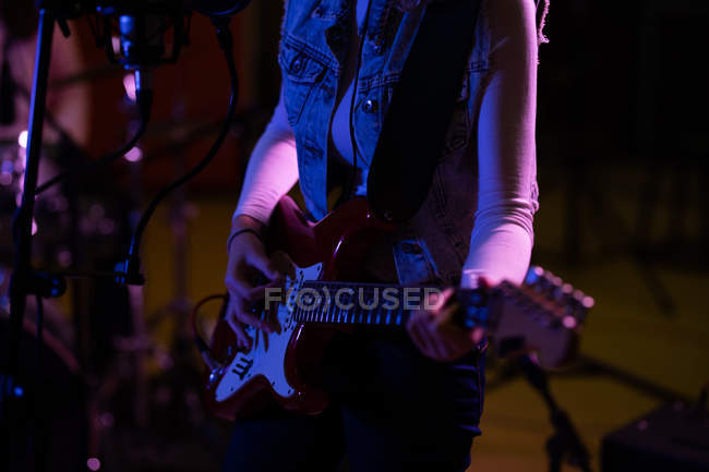 Vue latérale de la partie médiane d'une femme jouant de la guitare électrique lors d'une session dans un studio d'enregistrement — Photo de stock