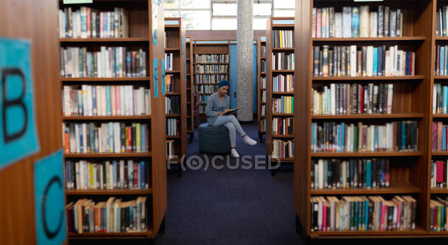 Передній погляд на молоду студентку з Азії, одягнену в тюрбан, яка читає книжку і навчається в бібліотеці. — стокове фото