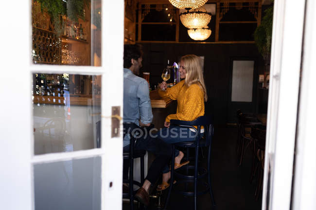 Vue latérale d'un jeune couple caucasien heureux se détendre ensemble en vacances dans un bar — Photo de stock