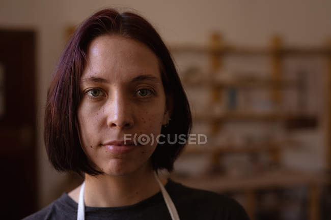 Retrato close-up de uma jovem cerâmica caucasiana olhando diretamente para a câmera em um estúdio de cerâmica — Fotografia de Stock