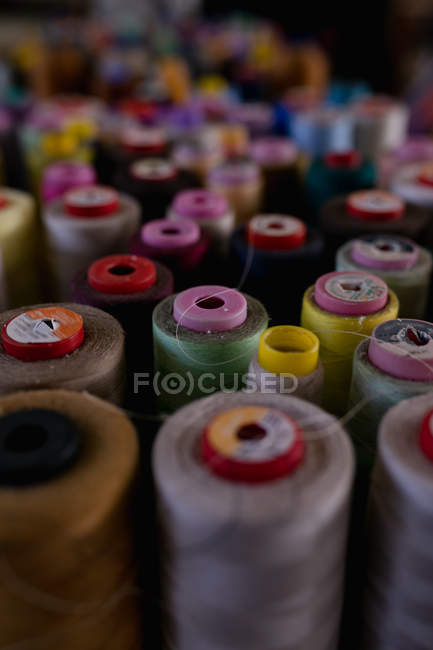 Боббіни з кольоровими нитками на передньому плані майстерні на капелюшній фабриці — стокове фото