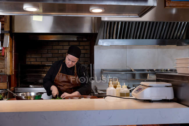 Front view of a young Caucasian female chef preparing ingredients at a counter in a restaurant kitchen — Stock Photo
