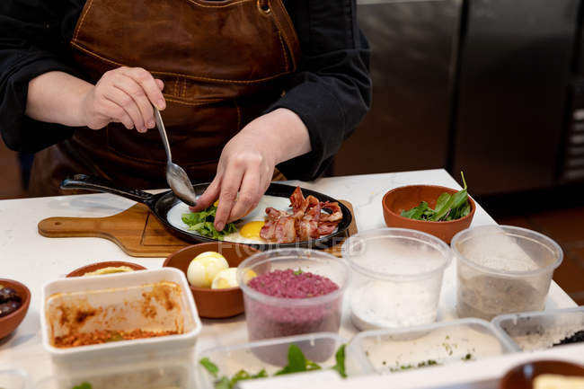 Vista frontal no meio da seção do chef feminino organizando comida para ser servida em uma panela em uma cozinha do restaurante — Fotografia de Stock