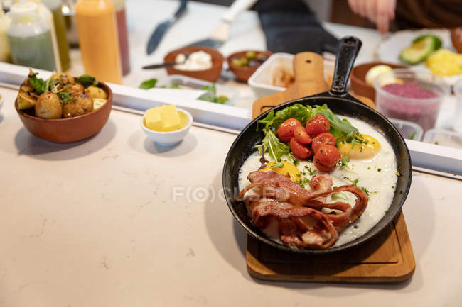 Vista frontal de un plato preparado en una sartén en una cocina de restaurante, listo para ser llevado y servido a un cliente - foto de stock