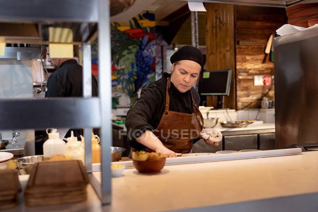 Front view close up of a young Caucasian female chef working at a counter in a restaurant kitchen — Stock Photo