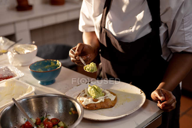 Vista frontale metà sezione di chef donna preparare un piatto in una cucina ristorante — Foto stock