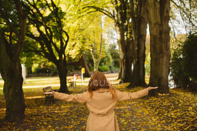 Visão traseira da mulher de pé no parque com os braços abertos . — Fotografia de Stock