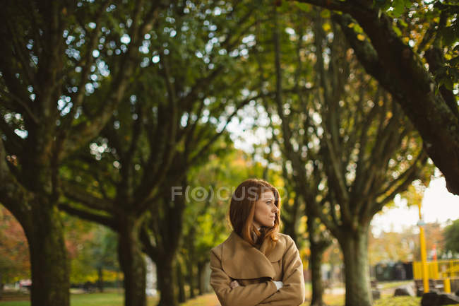 Женщина со скрещенными руками стоит в парке . — стоковое фото