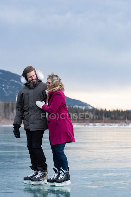 Vista lateral de la feliz pareja caucásica interactuando entre sí mientras están de pie en el paisaje nevado natural - foto de stock