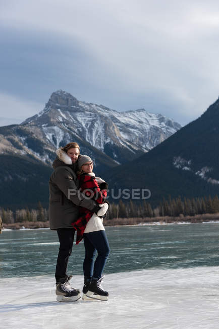 Retrato de feliz pareja caucásica de pie con el brazo alrededor en el paisaje nevado natural en el fondo . - foto de stock
