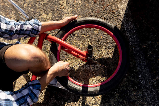 Вид сверху на низкое сечение человека, ремонтирующего колесо — стоковое фото