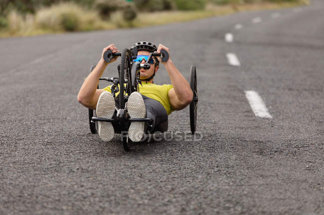 Вид на молоду Кавказьку людину в спортивному одязі на лежачому велосипеді велоспорту на заміському шляху — стокове фото