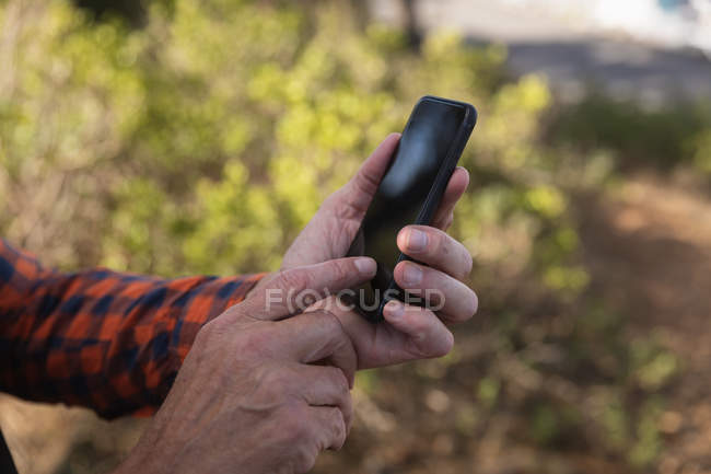 Close up of hands of man using a smartphone during a walk in a rural setting — Stock Photo
