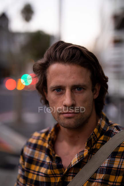 Portrait gros plan d'un jeune homme caucasien regardant la caméra debout dans une rue de la ville dans la soirée — Photo de stock