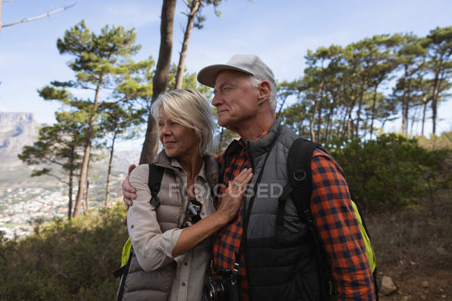 Vista lateral de um homem e mulher caucasiano maduro abraçando durante uma caminhada em um ambiente rural — Fotografia de Stock