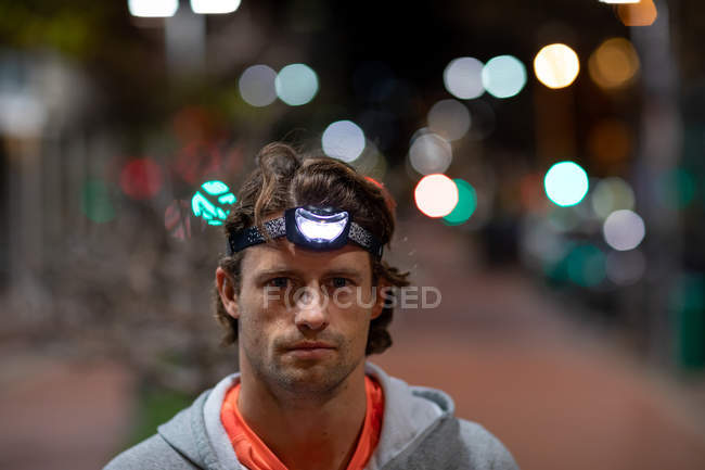Portrait of a young Caucasian man in the street looking to camera with a headlamp on — Stock Photo