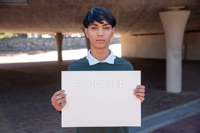 Porträt einer jungen Transgender-Person mit gemischter Rasse, die ein leeres Schild hält — Stockfoto