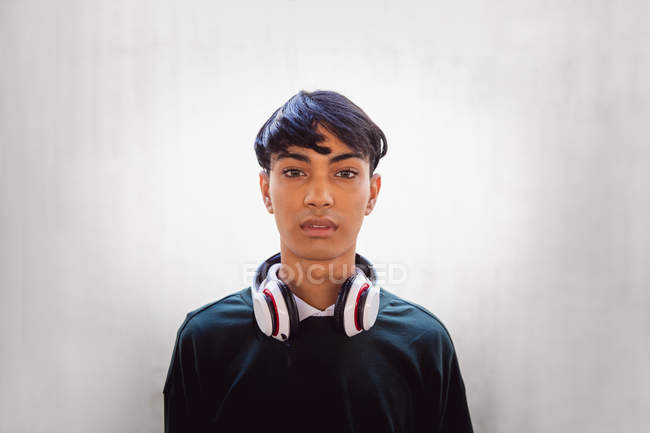 Retrato de un joven transgénero mestizo de moda en la calle, contra una pared blanca - foto de stock