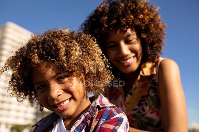 Vista frontal de cerca de una joven mestiza y su hijo preadolescente disfrutando del tiempo juntos en un día soleado - foto de stock
