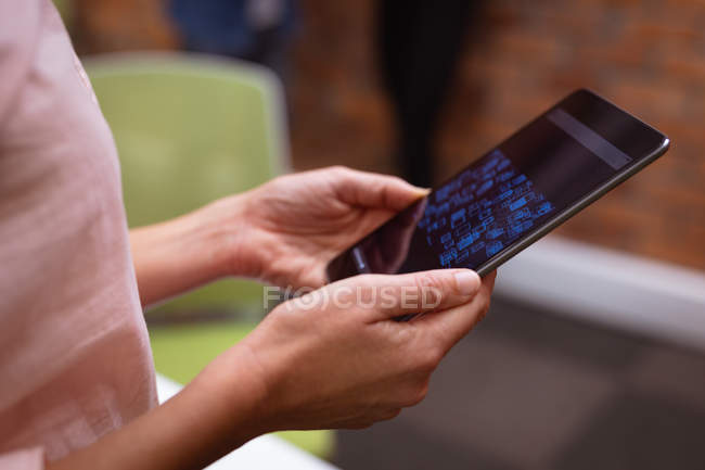 Seitenansicht mittlerer Abschnitt der Frau mit einem Tablet-Computer arbeiten im Büro eines kreativen Unternehmens — Stockfoto