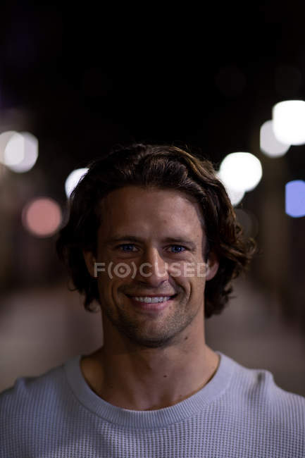 Портрет крупним планом молодого Кавказького чоловіка на вулиці усміхнений фотоапарат у вечірній час — стокове фото