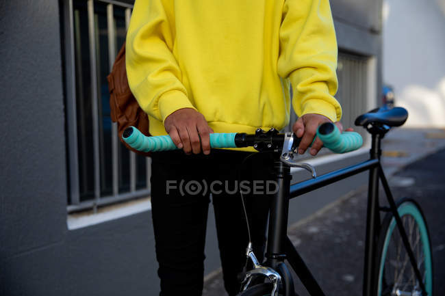 Vista frontal sección media de un hombre de moda en la calle, sosteniendo una bicicleta - foto de stock
