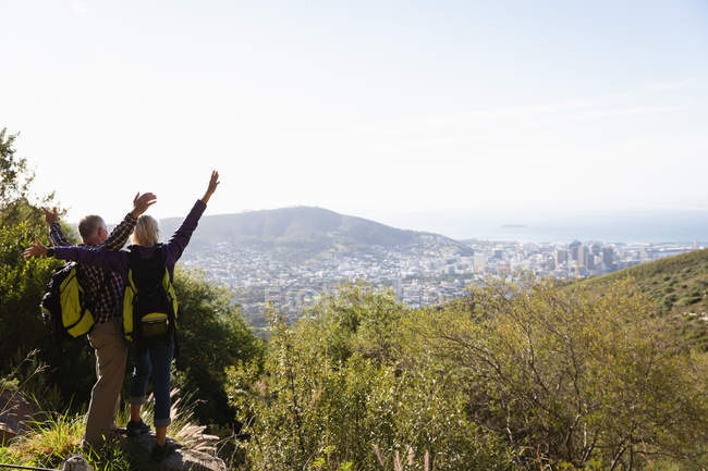 Rear view of a mature Caucasian man and woman celebrating with their arms up in the air during a walk in a rural setting — Stock Photo