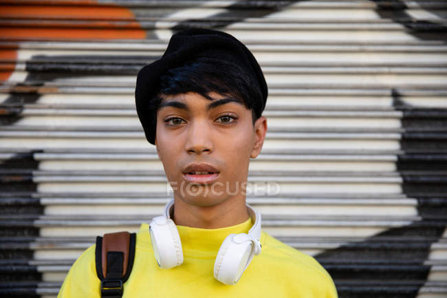 Ritratto di un giovane transgender transgender di moda per strada, con un basco con dei graffiti sullo sfondo — Foto stock