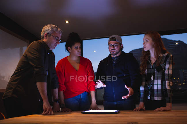 Vista frontal de um grupo diversificado de criativos em pé junto a uma mesa em uma sala de conferências de escritório, em uma discussão em uma reunião — Fotografia de Stock
