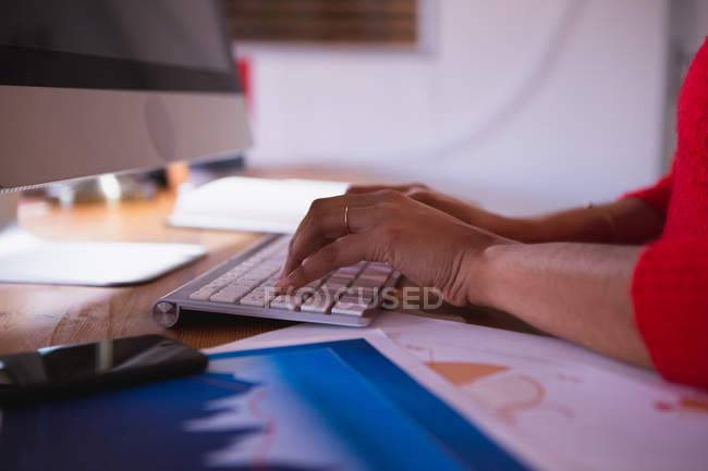 Hands of woman working in a creative office, sitting at a desk typing on a computer keyboard — Stock Photo