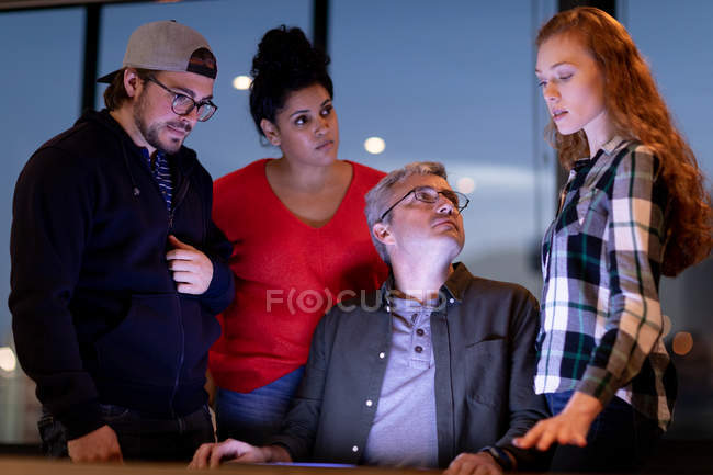 Vista frontale di un gruppo eterogeneo di creativi accanto a un tavolo in una sala conferenze dell'ufficio, in una discussione in una riunione . — Foto stock
