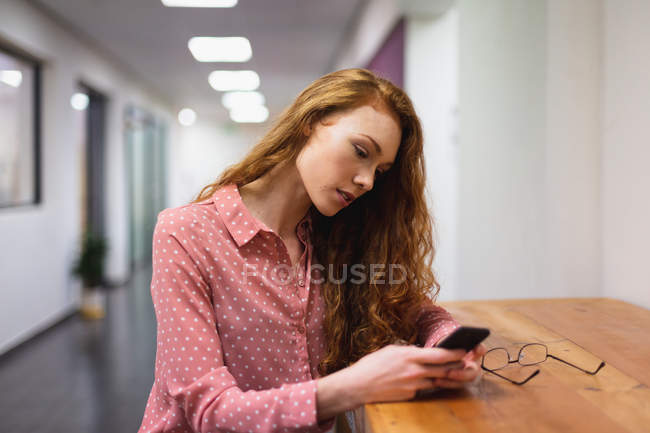 Vista lateral de uma jovem caucasiana trabalhando em um escritório criativo usando um smartphone. Isto é um negócio de arranque. — Fotografia de Stock