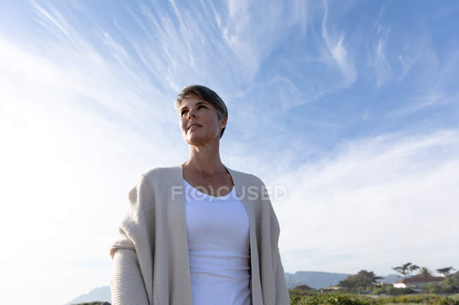 Vista frontal de perto de uma mulher caucasiana de meia-idade desfrutando de tempo livre em um dia ensolarado. Ela está pensando e olhando para longe . — Fotografia de Stock