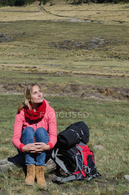 Vista ad alto angolo di donna premurosa che guarda lontano mentre si siede sulla roccia — Foto stock