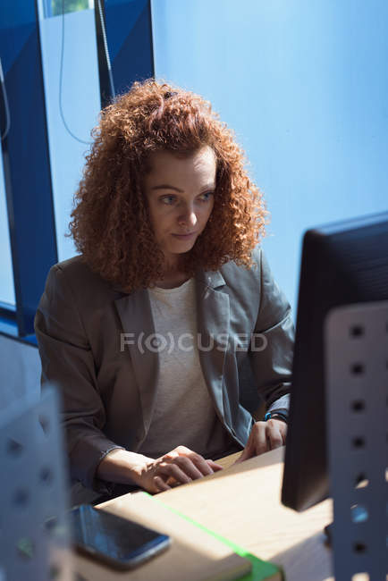 Жінка-студент використовує настільний комп'ютер, сидячи за столом у класі — стокове фото