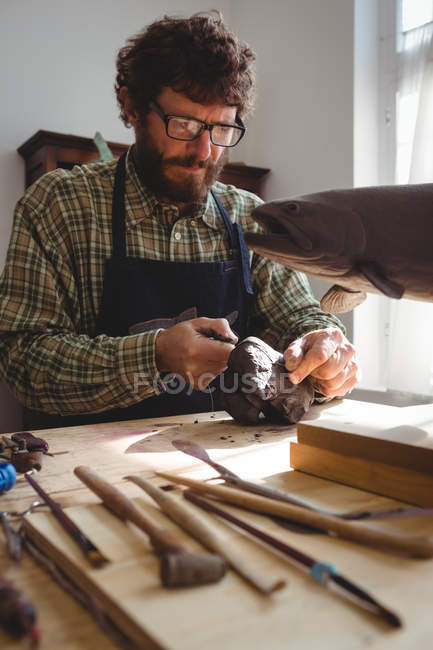 Craftsman working on clay sculpture in workshop — Stock Photo
